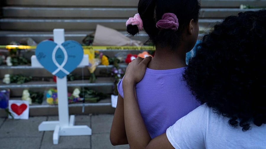 Bria Ferrell, 18, embraces her sister Brittany Ferrell, 12, at the memorial outside of the Old National Bank on April 11, 2023 in Louisville, Kentucky. On the morning of April 10, a gunman opened fire inside the Old National Bank building killing four people. A fifth victim later died in the hospital. Credit: AFP Photo