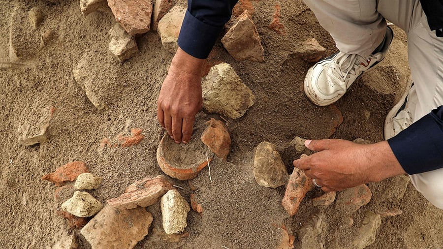 In this picture taken on March 31, 2023, archaeologist Aqeel Mansarawi searches for pottery sherds at the Umm al-Aqarib archaeological site, frequently buried by sandstorms due to desertification, in the district of al-Rifai in Iraq's southern Dhi Qar province. Credit: Asaad NIAZI / AFP