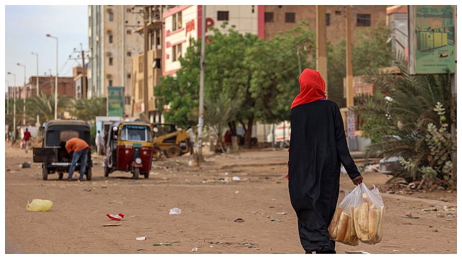 A woman walks with bags of bread along a street in Sudanese capital Khartoum on April 18, 2023. Credit: AFP Photo
