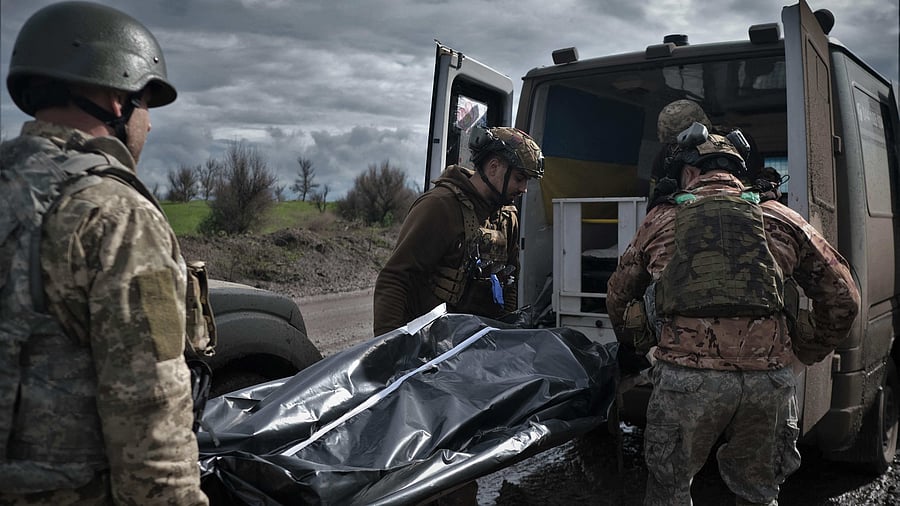Ukrainian servicemen and paramedics load a bag containing the body of a fallen Ukrainian serviceman in to a medical evacuation vehicle on a road near Bakhmut. Credit: AFP Photo