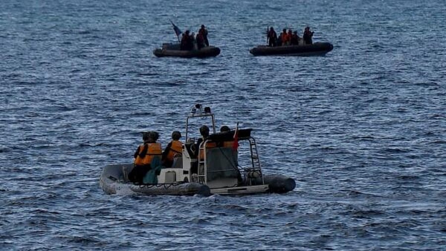 Chinese coast guard personnel (front) aboard their rigid hull inflatable boat observing Philippine coast guard personnel. Credit: AFP Photo
