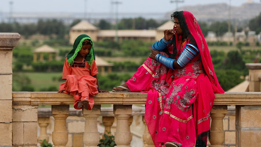 A Pakistani Hindu devotee woman and a girl sit while waiting with others for transport before leaving to pay homage at Hinglaj Mata Temple in Balochistan, outside the Shri Ratneshwar Mahadev Temple in Karachi. Credit: AFP Photo