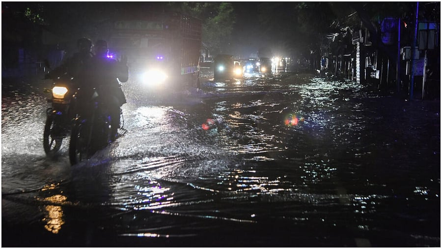 Hyderabad: Commuters wade through a waterlogged road after heavy rainfall, in Hyderabad, early Monday, May 1, 2023. Credit: PTI Photo