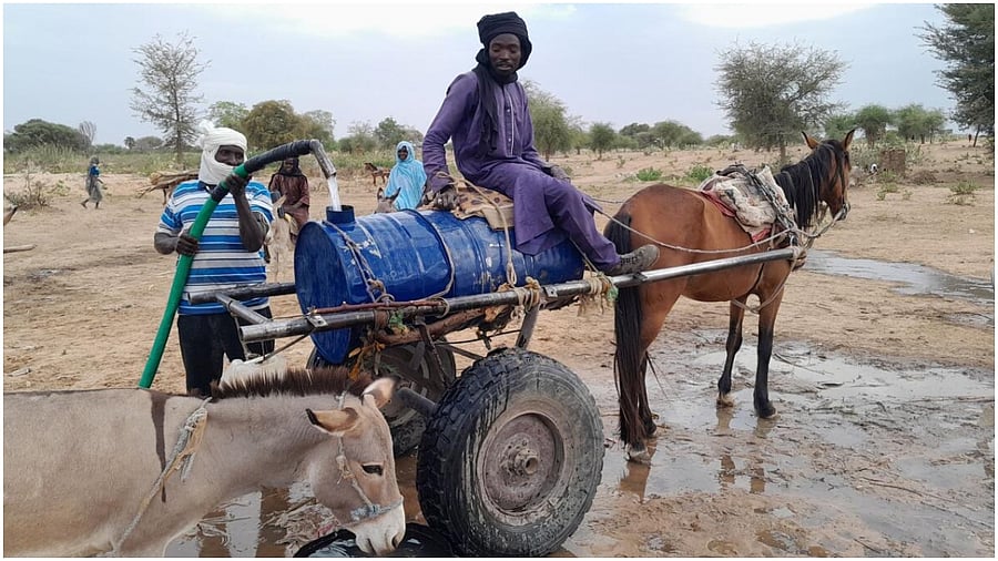 Mahamat Bechir Abdallah, a Sudanese refugee who fled the violence in his country, fills a container as he sells water to the other refugees near the border between Sudan and Chad, in Koufroun, Chad May 1, 2023.  Credit: Reuters Photo