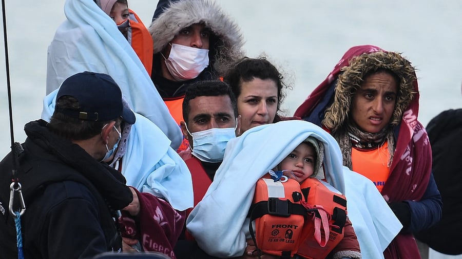 Migrants, picked up at sea while attempting to cross the English Channel, are helped by a member of the UK Border Force to disembark from a boat, in the Marina at the Dover port, on May 3, 2022, in Dover, on the south-east coast of England. Credit: AFP File Photo