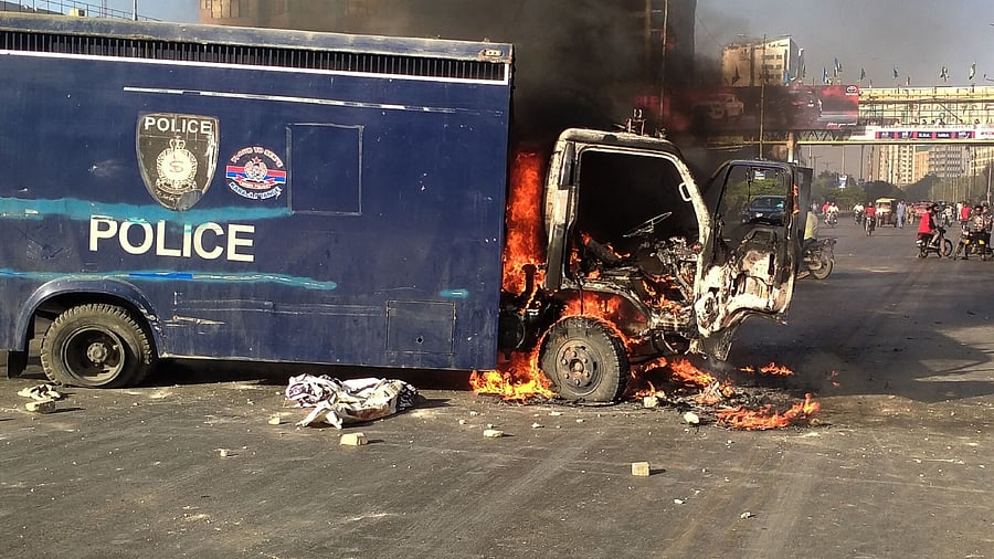 A police vehicle is seen burning along a road during a protest by Pakistan Tehreek-e-Insaf party activists and supporters of former Pakistan's Prime Minister Imran against the arrest of their leader. Credit: AFP Photo