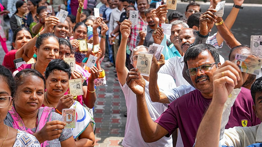 People wait in queues at a polling station to cast their votes for Karnataka Assembly elections, in Bengaluru, Wednesday. Credit: PTI Photo