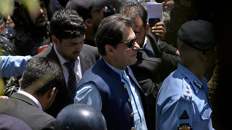 Pakistan's former Prime Minister Imran Khan, center, is escorted by police officers as he arrives to appear in a court. Credit: AP Photo