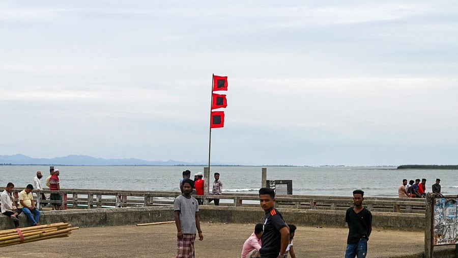 People gather beside a storm danger signal flag in Shahpori island jetty in Bangladesh. Credit: AFP