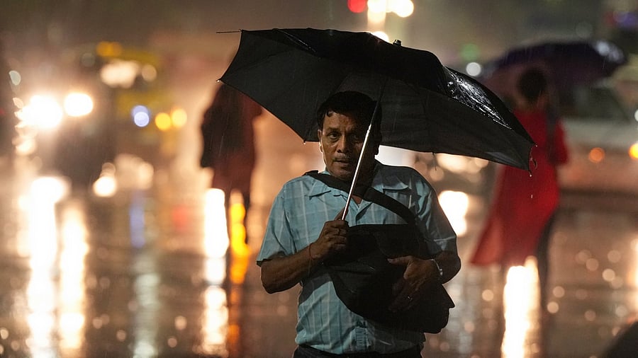 A commuter walks under the umbrella during rain in Kolkata, Monday, May 15, 2023. Credit: PTI Photo