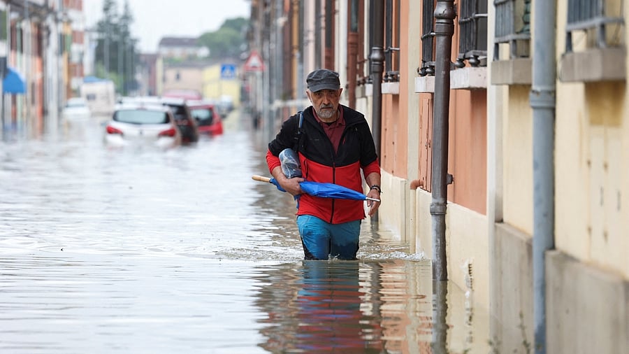 A man wades through floodwaters after heavy rains hit Italy's Emilia Romagna region, in Lugo, Italy. Credit: Reuters Photo