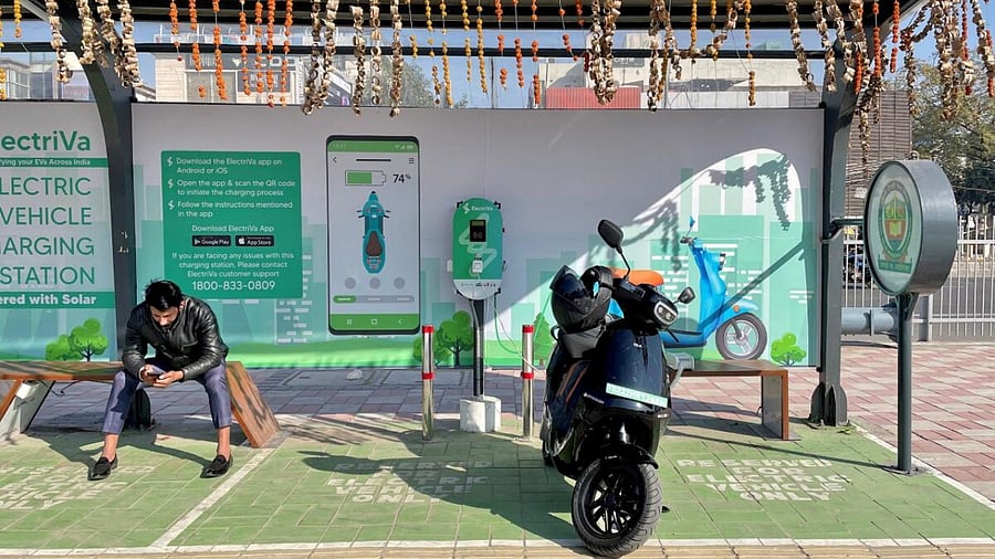 Man waits for his Ola Electric scooter to charge. Credit: Reuters File Photo
