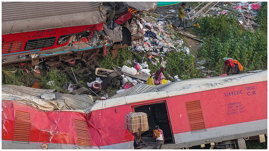 Porters carry goods collected from the mangled coaches at the triple train mishap site where over 270 people died and more than 1000 injured. Credit: PTI Photo
