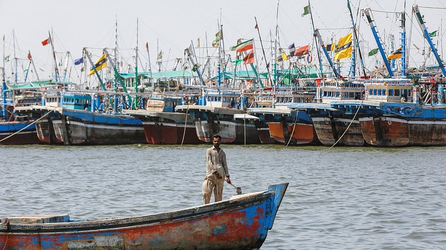 A man sails on a boat past anchored fishing boats, after a ban was imposed on coastal activities following the cyclonic storm, Biparjoy, over the Arabian Sea, at the Ibrahim Hyderi fishing village on the outskirts of Karachi, Pakistan June 12, 2023. Credit: Reuters Photo