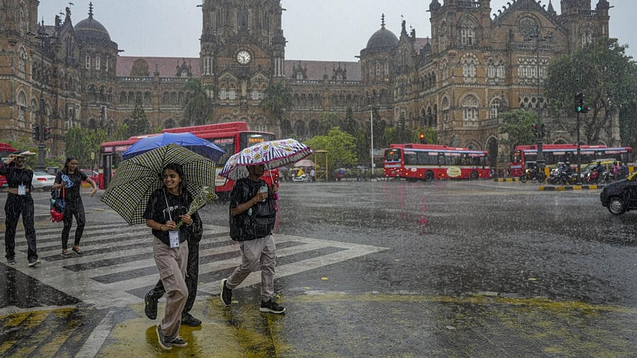 Pedestrians cross road during rain, at Chhatrapati Shivaji Maharaj Terminus, in Mumbai, Saturday, June 24, 2023. Credit: PTI Photo
