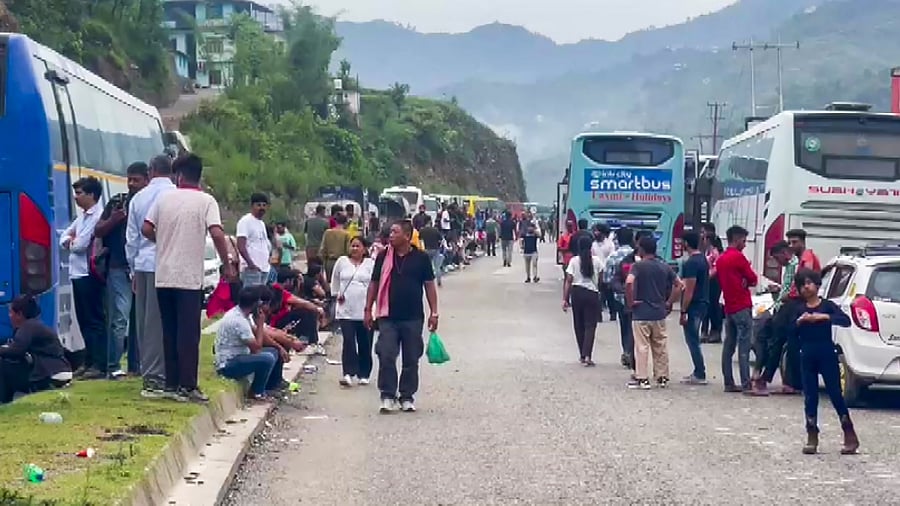 Commuters wait for the clearing of blocked Chandigarh-Manali highway following a landslide triggered by continuous rain in Himachal Pradesh, in Mandi district, Monday, Jun 26, 2023. Credit: PTI Photo