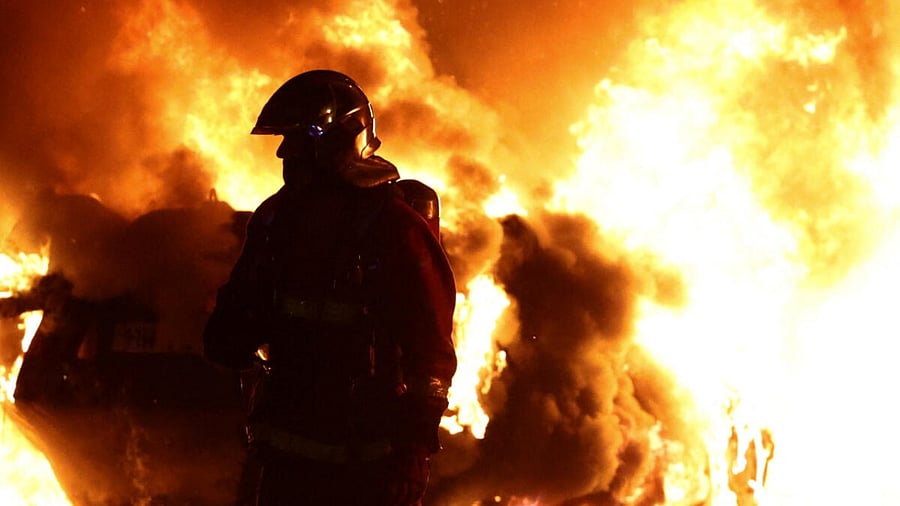 A firefighter stands in front of a burning vehicle during clashes between protesters and police, after the death of Nahel, a 17-year-old teenager killed by a French police officer during a traffic stop, in Nanterre, Paris suburb, France, June 28, 2023. Credit: Reuters Photo