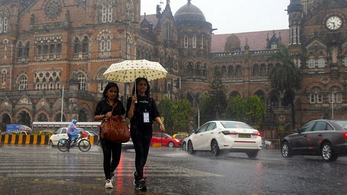 Women hold an umbrella as they walk on the street amid heavy rain in Mumbai. Credit: IANS File Photo