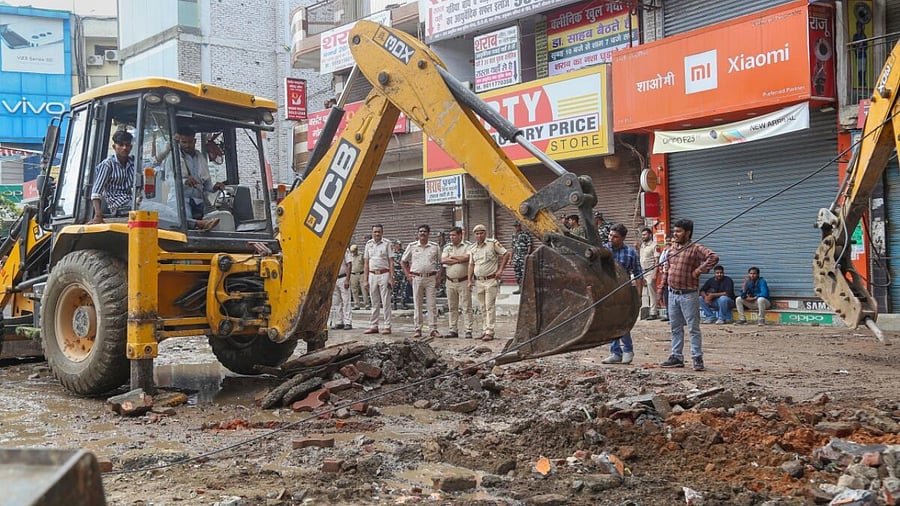 A bulldozer being used to demolish two religious structures for the construction of a flyover, during a drive by PWD, at Bhajanpura area in New Delhi. Credit: PTI Photo