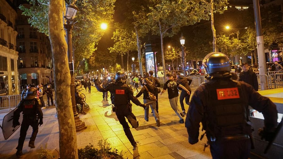 People run followed by police officers during riots following the death of Nahel, a 17-year-old teenager killed by a French police officer in Nanterre during a traffic stop, at Champs Elysees in Paris, France, July 1, 2023. Cred