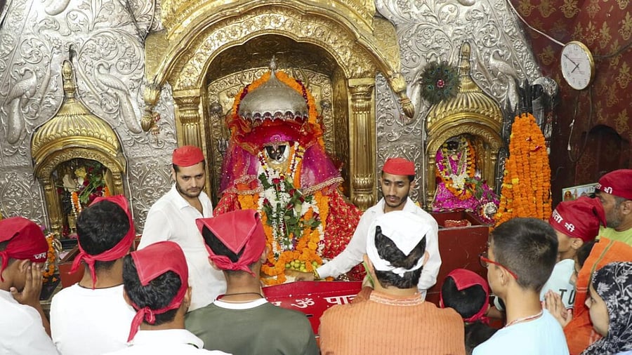 Devotees with their heads covered offer prayers at Bawe Wali Mata temple, in Jammu. Credit: PTI Photo