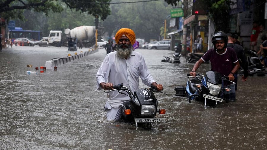 A man on his motorbike wades through a flooded street after heavy rains in New Delhi. Credit: Reuters Photo