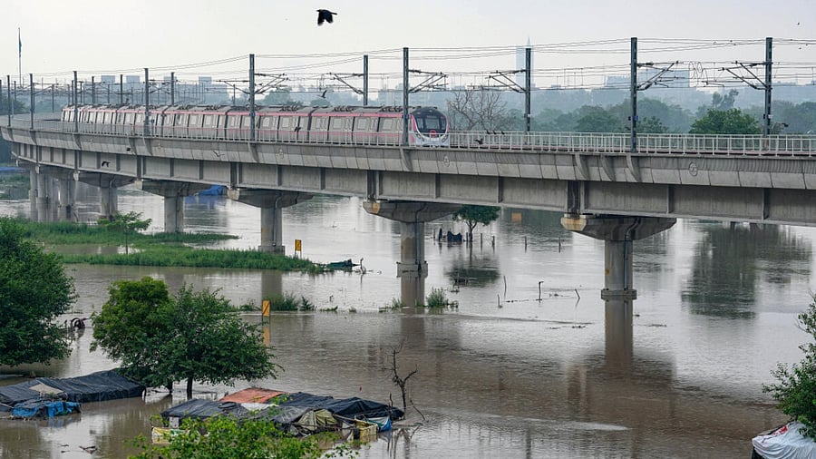 A Delhi Metro train passes by as the swollen Yamuna river floods low-lying areas, in New Delhi. Credit: PTI Photo