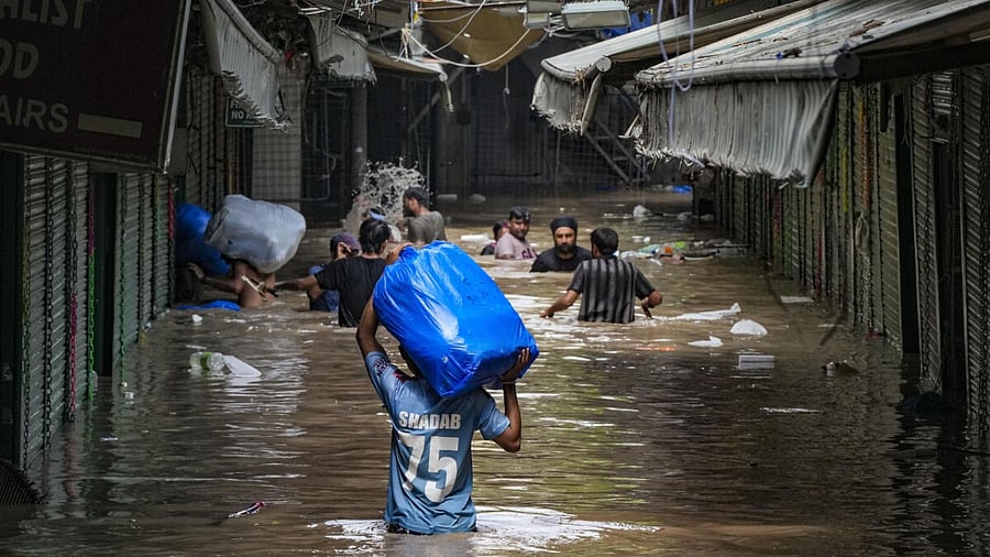 Locals wade through the flooded Monastery market following monsoon rains, in New Delhi, Wednesday, July 12, 2023. Credit: PTI Photo