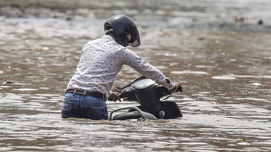 A motorist wades through a flooded road near the Red Fort as the swollen Yamuna river floods low-lying areas, in New Delhi, Thursday, July 13, 2023. Credit: PTI Photo