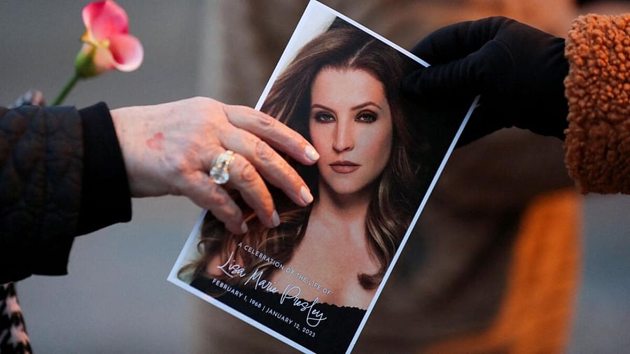  A music fan hands a picture of Lisa Marie Presley to another fan as they attend a public memorial for her, the only daughter of the "King of Rock 'n' Roll," Elvis Presley, at Graceland Mansion in Memphis, Tennessee, U.S. January 22, 2023. Credit: Reuters Photo