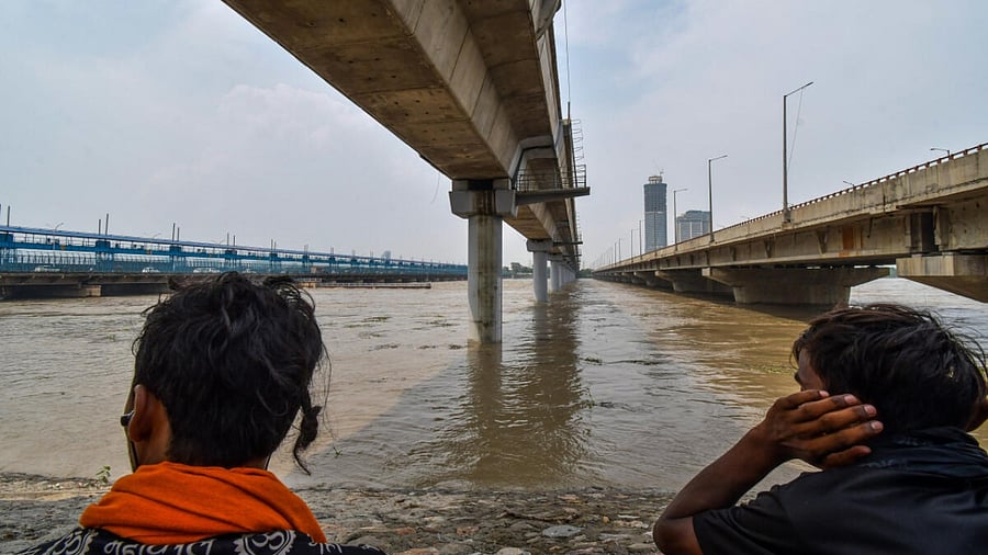 Locals watch swollen Yamuna river following monsoon rains, near Kalindi Kunj in New Delhi, Friday, July 14, 2023. Credit: PTI Photo