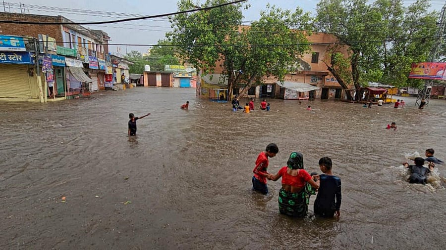 Locals wade through a flooded area after heavy monsoon rains, in Fatehpur, Wednesday, July 5, 2023. Credit: PTI Photo