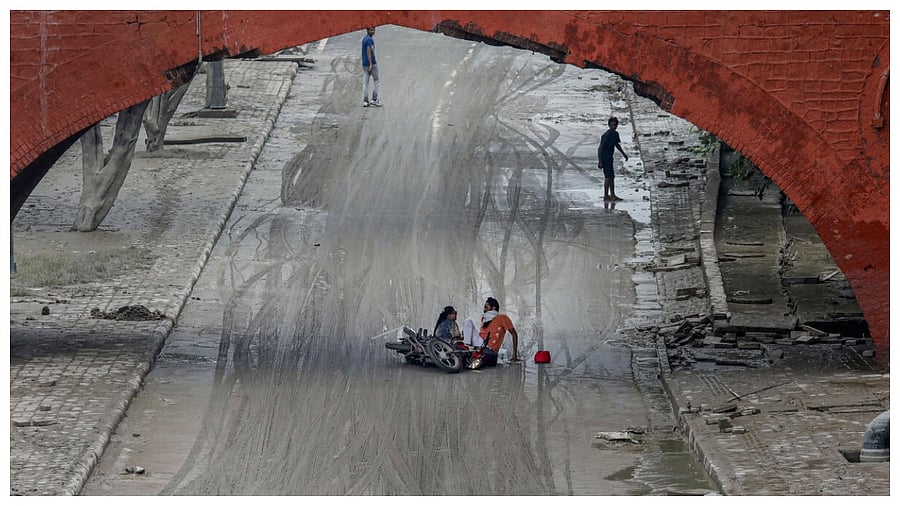 A motorcyclist falls down due to the slippery road near the Red Fort after Yamuna floodwater receded in New Delhi, Monday, July 17, 2023. Credit: PTI Photo