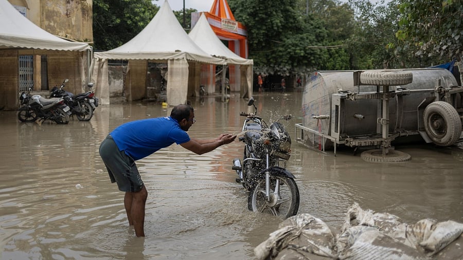 A man cleans his bike with the muddy water outside his house after flood water recedes from a residential area that was flooded by the overflowing of the river Yamuna following heavy rains, in New Delhi, India, July 17, 2023. Credit: Reuters Photo