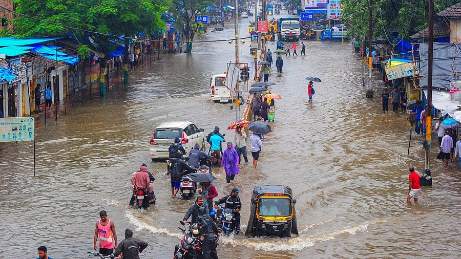 Commuters on a waterlogged road during monsoon rainfall. Credit: PTI Photo