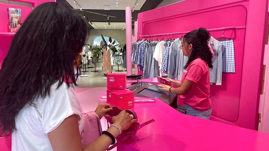 A shopper looks on a pink Barbie-themed purse while a shop assistant works during the Barbie pop-up in Zara's Soho store in New York City. Credit: Reuters Photo