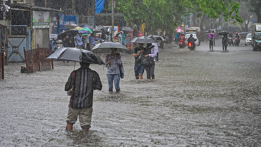 People wade through a waterlogged road amid monsoon rains at Andheri, in Mumbai. Credit: PTI Photo