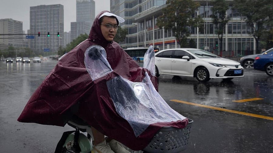 A man rides an electric scooter during heavy rain in Beijing, China. Credit: Reuters Photo