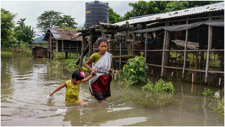 Morigaon: A woman and a child wade through the floodwaters, in Morigaon district. Credit: PTI Photo