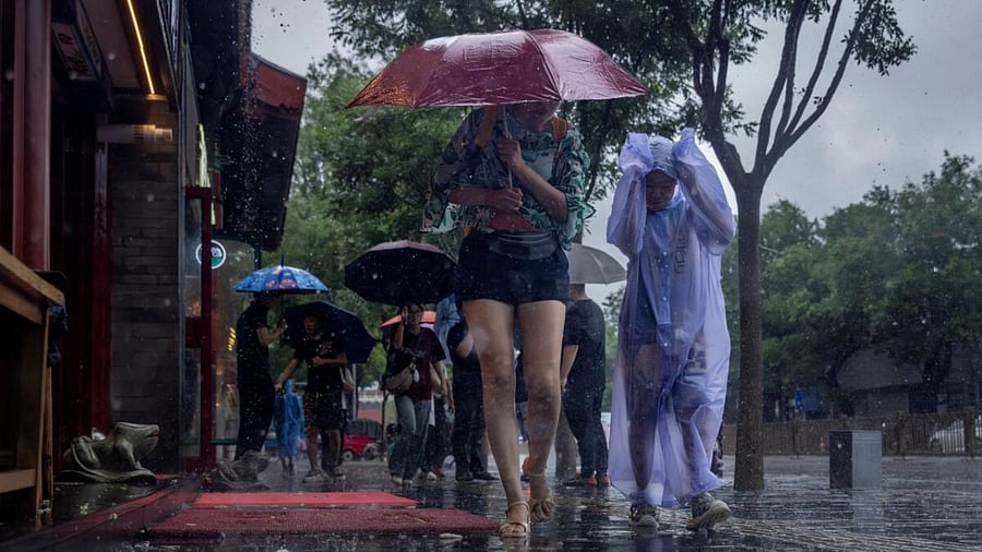 People wear raincoats and shelter under umbrellas in a tourist area during heavy rain in Beijing, China, July 30, 2023. Credit: Reuters Photo