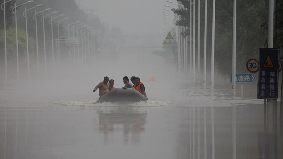 People ride a boat through a flooded road after the rains and floods brought by remnants of Typhoon Doksuri, in Zhuozhou, Hebei province, China August 3, 2023. Credit: Reuters Photo