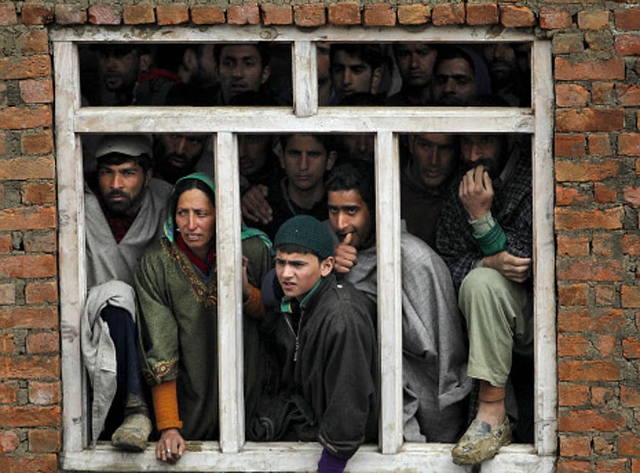 Villagers watch the rescue operation at the site of a damaged house after a hillside collapsed onto a house at Laden village. Reuters