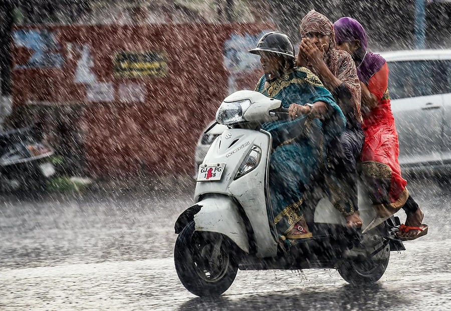 Commuters make their way across a street during heavy rain, in Ahmedabad on Monday, July 02, 2018. (PTI Photo)
