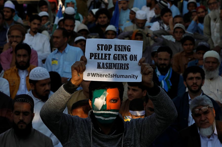 A supporter of religious and political party Jamaat-e-Islami (JI), with his face painted in Kashmir's flag colours, holds a sign as he takes part in a rally to mark Kashmir Solidarity Day in Karachi, Pakistan, February 5, 2019. REUTERS/Akhtar Soomro