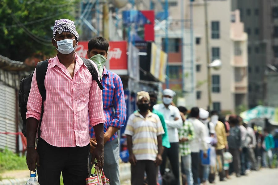 Migrant labourers wait in a queue to board the specially arranged government bus to return to their homes during a government-imposed nationwide lockdown as a preventive measure against the COVID-19 coronavirus, in Kolkata on April 29, 2020. (Photo by Dibyangshu SARKAR / AFP)