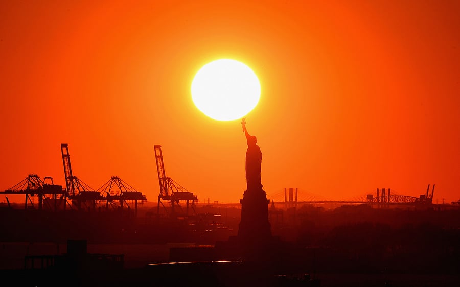 The sun sets behind the Statue of Liberty on November 16, 2020 in New York City. Credit: AFP Photo