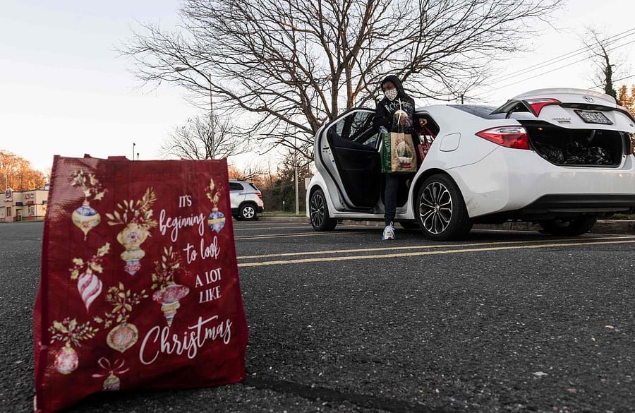 A volunteer helps arrange bags of food during a pre-Thanksgiving food handout, sponsored by Linda Flowers, for members of the community in Fort Washington, Maryland. Linda Flowers, a survivor of Covid-19, holds a community food handout each Friday to honor her late father, Bishop James N. Flowers, who passed away from Covid-19 in April 2020. Credit: AFP Photo