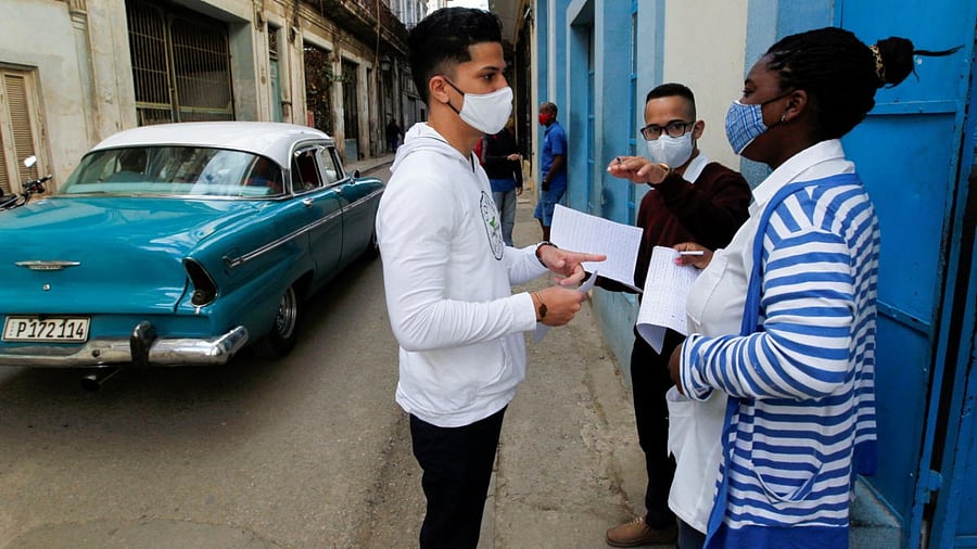 Medical students chat before talking to residents to find out who has symptoms of coronavirus disease (Covid-19), in Havana, Cuba, February 3, 2021. Credit: Reuters/Stinger.