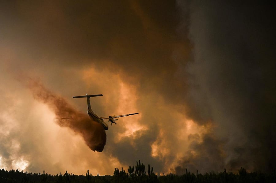A firefighting aircraft sprays fire retardant over trees during a wildfire near Belin-Beliet in Gironde, southwestern France. Credit: AFP Photo