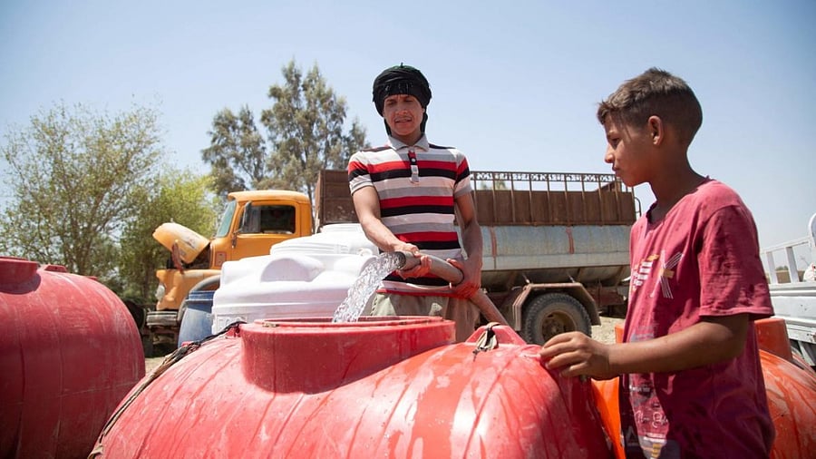 A boy collects water from a cistern amid shortage and high temperature in the village of al-Aghawat in Iraq's central Diwaniya province. Credit: AFP Photo